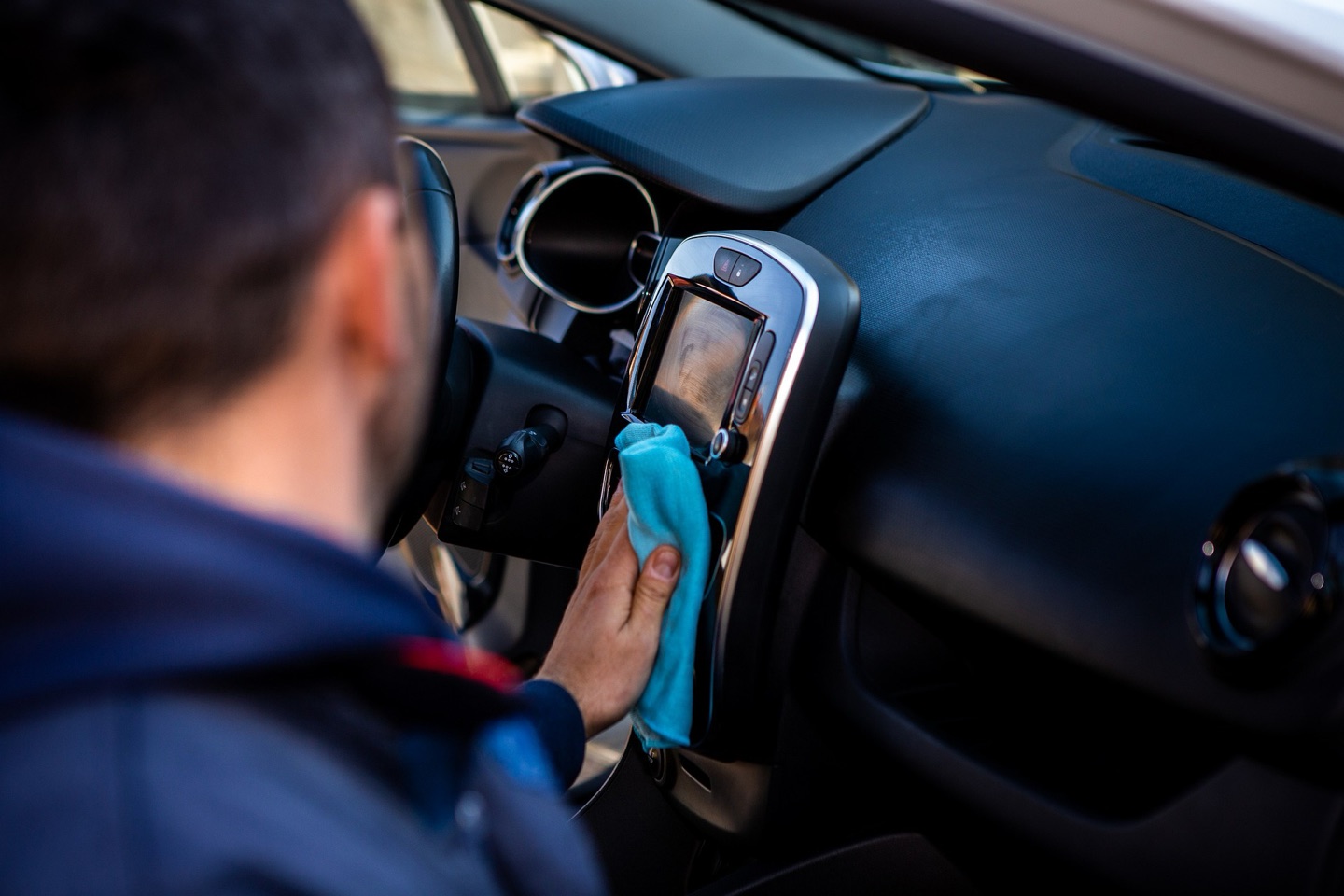 A driver wiping down the centre console of a car